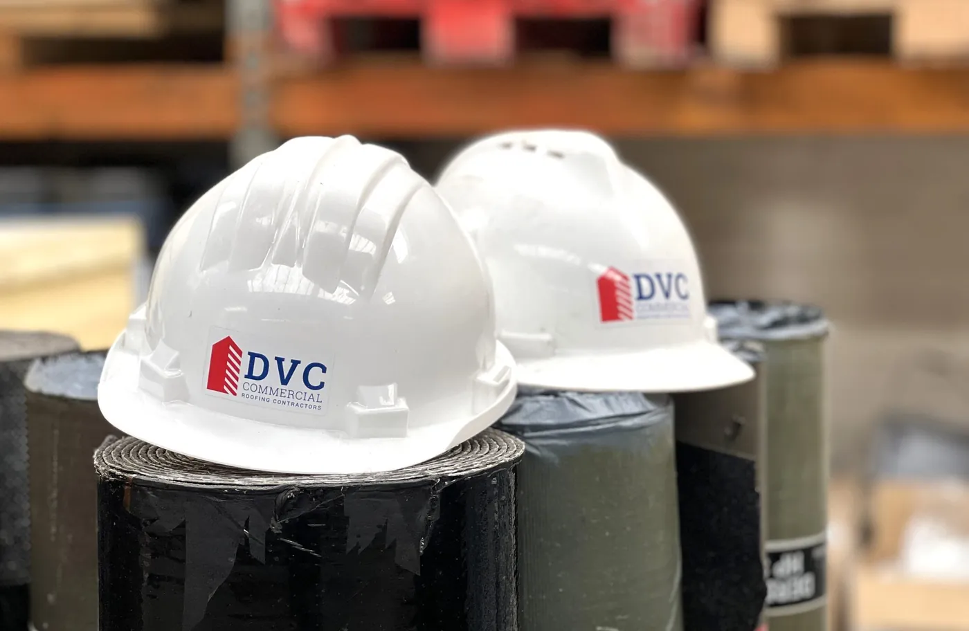 DVC branded hard hats on rolls of roofing membrane